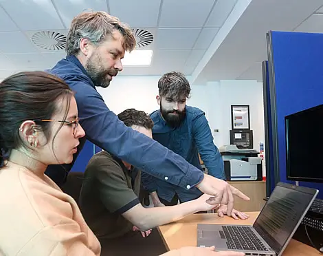 man explaining bioinformatics services provided by Isomerase to 3 people and pointing at a laptop